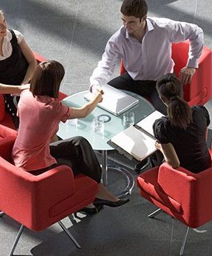 Group of people in red chairs at a business meeting du=discussing employment contract