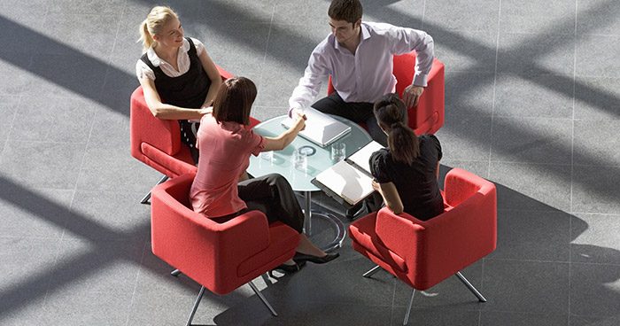 Group of people in red chairs at a business meeting du=discussing employment contract